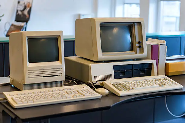 Two computers from the 1980s are standing on an office desk.