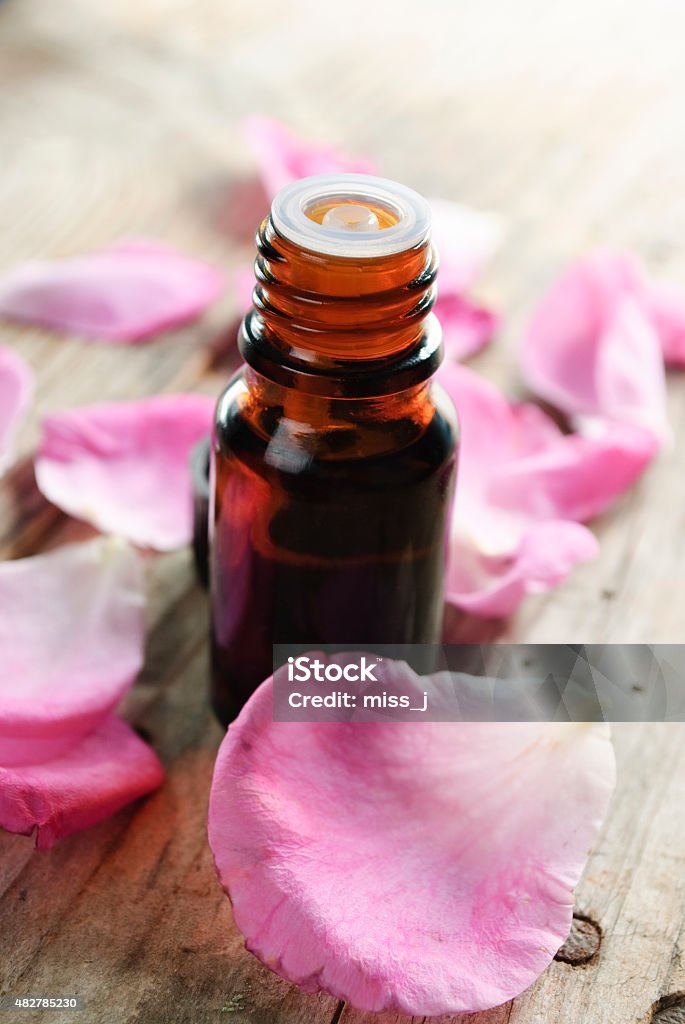 Essential Oil Essential oil with rose petals on wooden background Rose - Flower Stock Photo