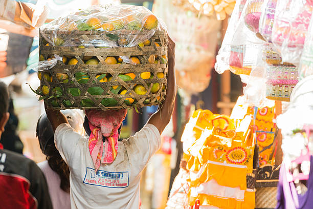 balinese uomo trasporta mangos in cesto con il tradizionale mercato indonesiano - service occupation candid small business carrying foto e immagini stock