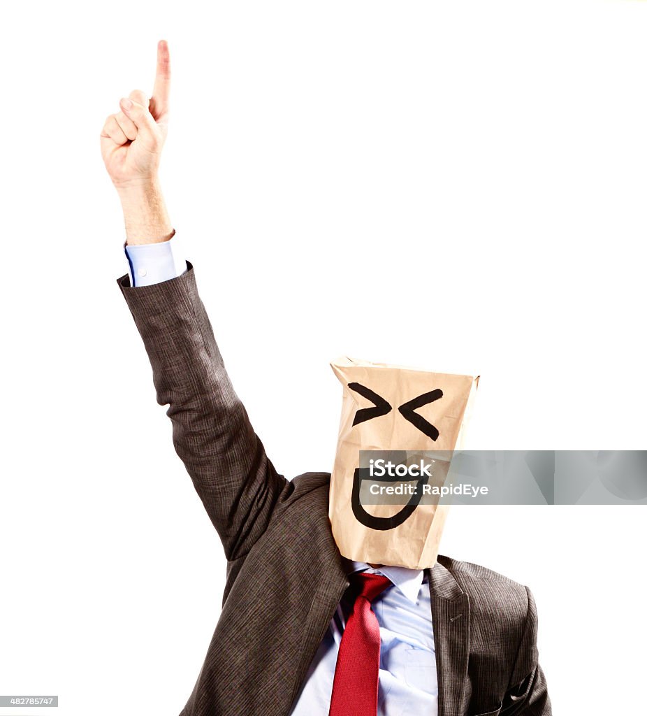 Businessman in paper-bag mask points upwards, laughing A mature businessman, in formal business clothes, wearing a mask made from a paper bag, showing a laughing face points upwards at something, laughing happily. Isolated on white. Adult Stock Photo