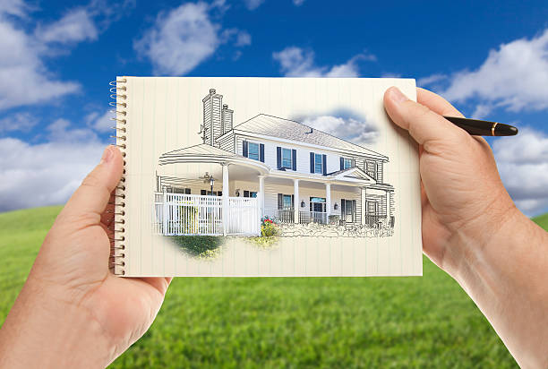 istock Hands Holding Paper With House Drawing Over Empty Grass Field 482785806