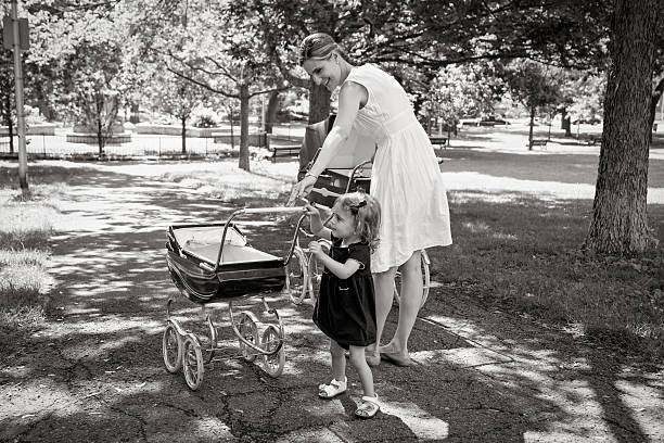 istock Mother and daughter walking babies in vintage prams. 482787056