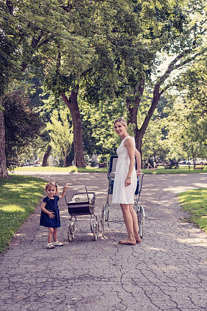 istock Mother and daughter walking babies in vintage prams. 482787068