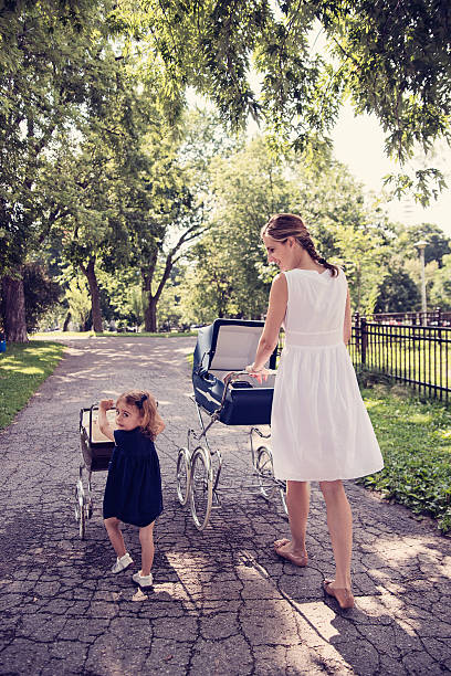istock Mother and daughter walking babies in vintage prams. 482787070