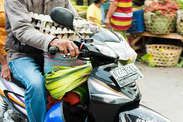 hombre balinés conducción a través de la tradicional con huevos de indonesia street market - service occupation candid small business carrying fotografías e imágenes de stock