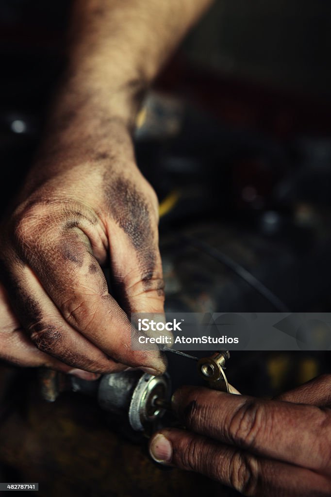 Mechanics hands. Mechanics' hands adjusting cable in engine bay of domestic car. Mechanic Stock Photo