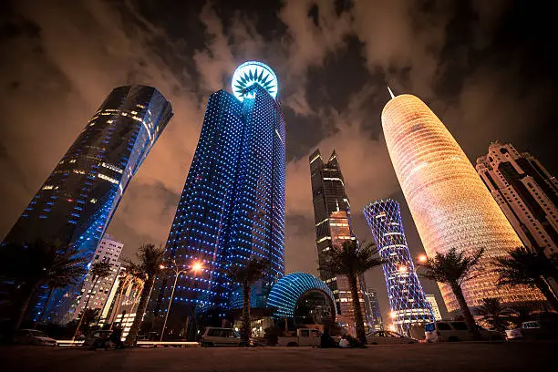 Futuristic modern skyscrapers illuminating the night at the corniche promenade in the capital city of Doha, Qatar, Middle East.