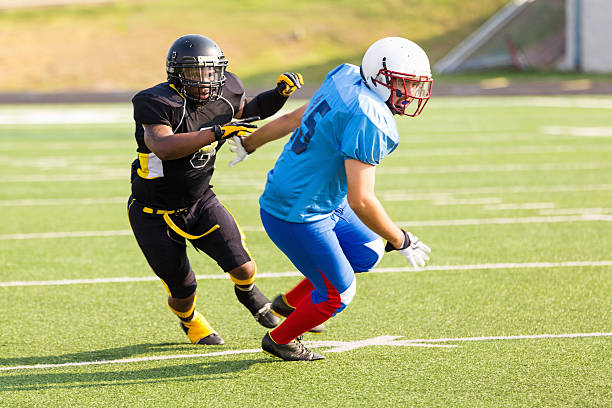 jogador de futebol de se preparar para enfrentar adversário durante pro jogo - football player group of people running american football - fotografias e filmes do acervo