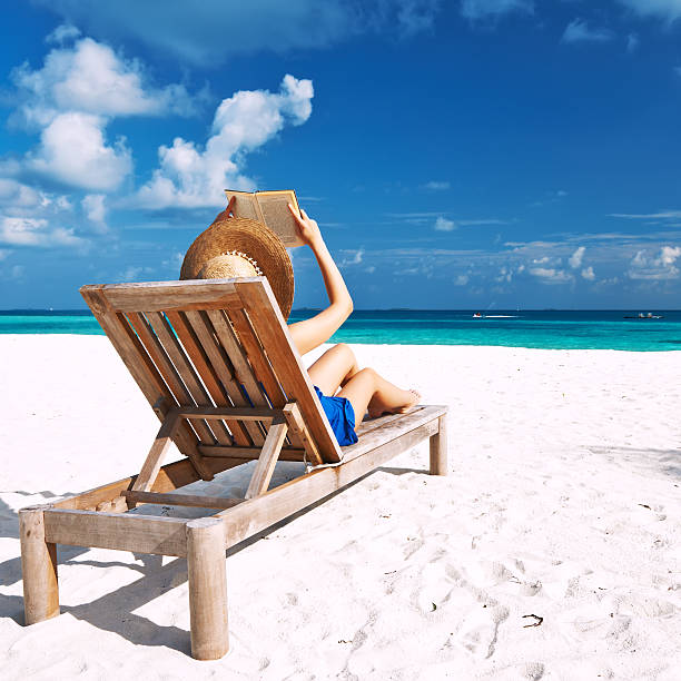 istock Young woman reading a book at beach 482789283
