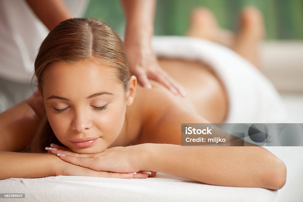 Enjoying in massage Young happy woman receiving back massage at spa and beauty salon Adult Stock Photo