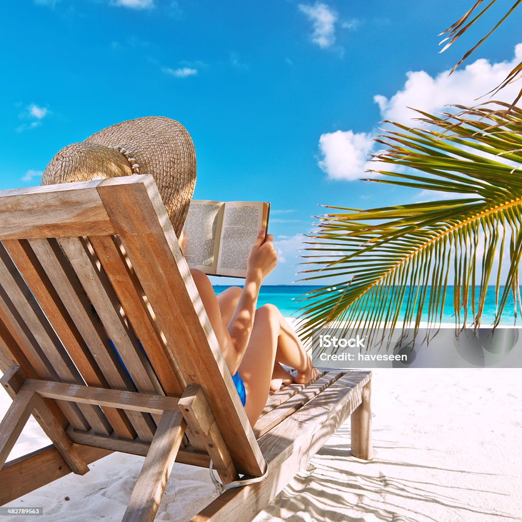 Young woman reading a book at beach Young woman reading a book at the beach Adult Stock Photo