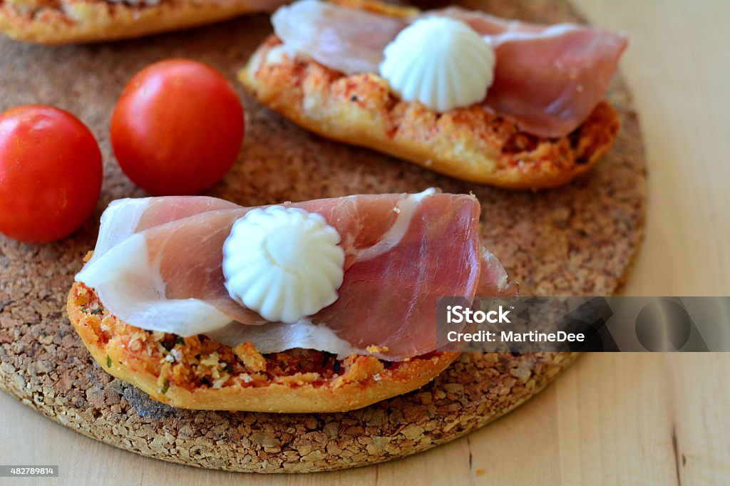 Bruschetta with oregano, prosciutto and mozzarella on a wooden table Italian Bruschetta With Mozzarella And Prosciutto On A Wooden Table 2015 Stock Photo