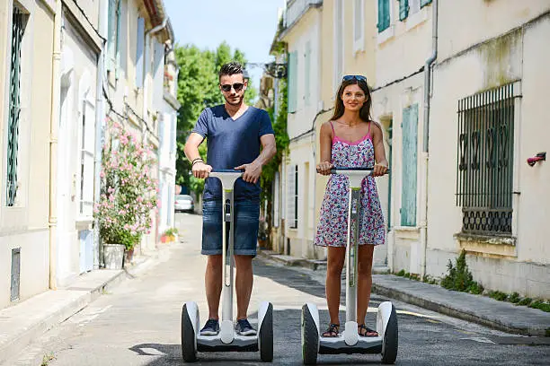 Happy young couple riding segway gyropode electric two wheels vehicule on a sightseeing tour