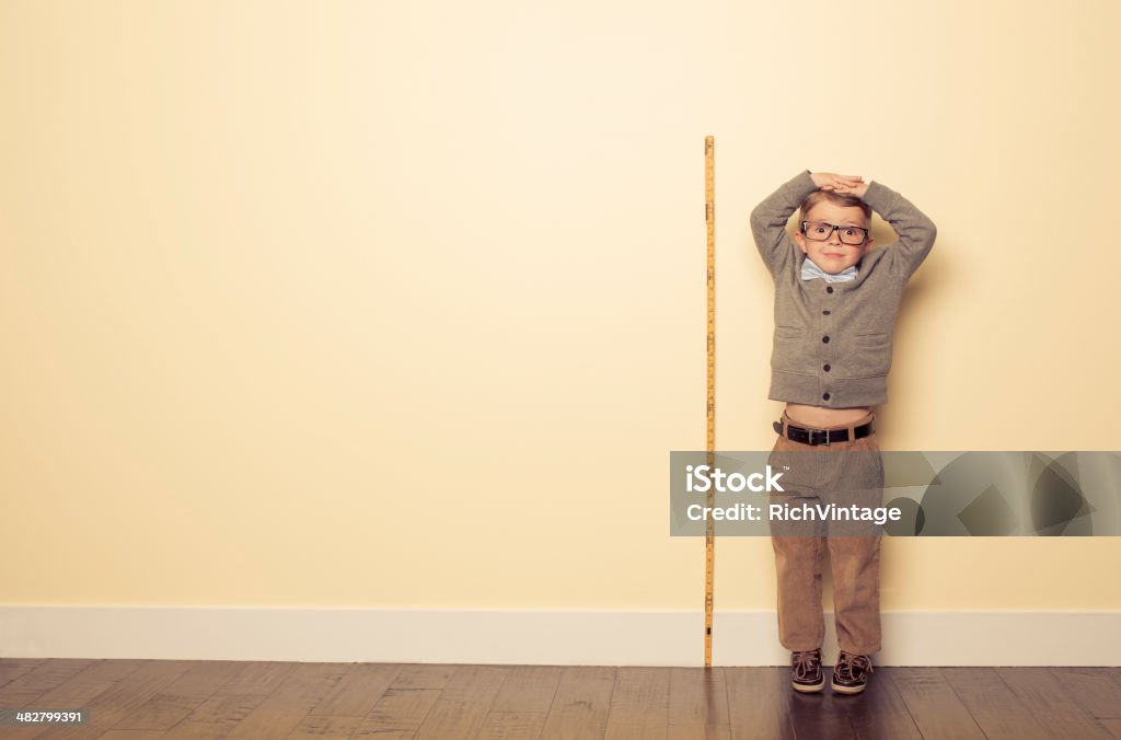Measuring Up A young boy is looking forward to growing and getting bigger.  Child Stock Photo
