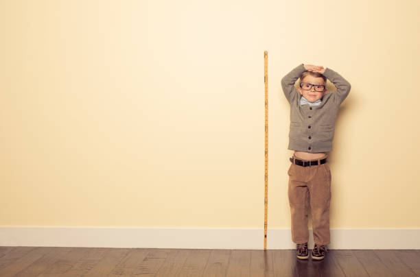 Measuring Up A young boy is looking forward to growing and getting bigger.  human height stock pictures, royalty-free photos & images