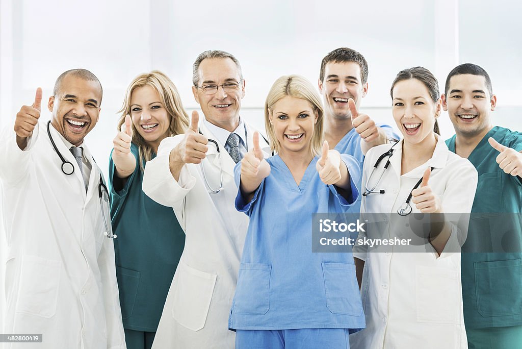 Doctors showing thumbs up. Group of cheerful doctors showing thumbs up and looking at the camera.    Thumbs Up Stock Photo