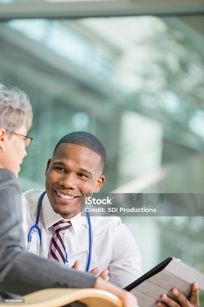 Senior paciente joven hablando con el médico acerca de los resultados de la prueba - Foto de stock de Doctor libre de derechos