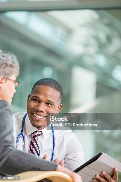 Senior Paciente Joven Hablando Con El Médico Acerca De Los Resultados De La Prueba Foto de stock y más banco de imágenes de Doctor