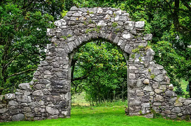 Photo of Old stone entrance wall in green garden