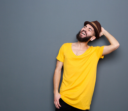 Close up portrait of a confident young man with beard smiling on gray background