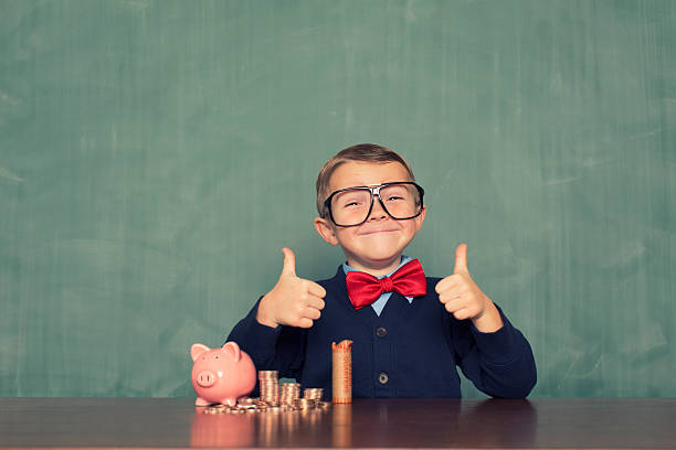 młody chłopiec nerd oszczędza pieniądze w jego świnka skarbonka - chytra zdjęcia i obrazy z banku zdjęć
