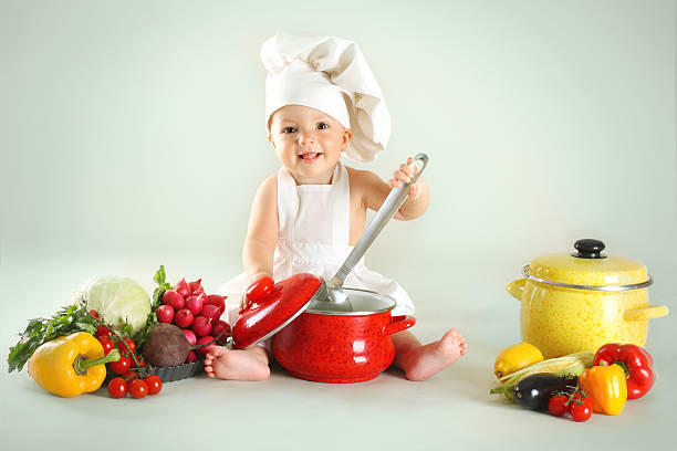 istock Baby wearing a chef hat with vegetables and pan 482805947