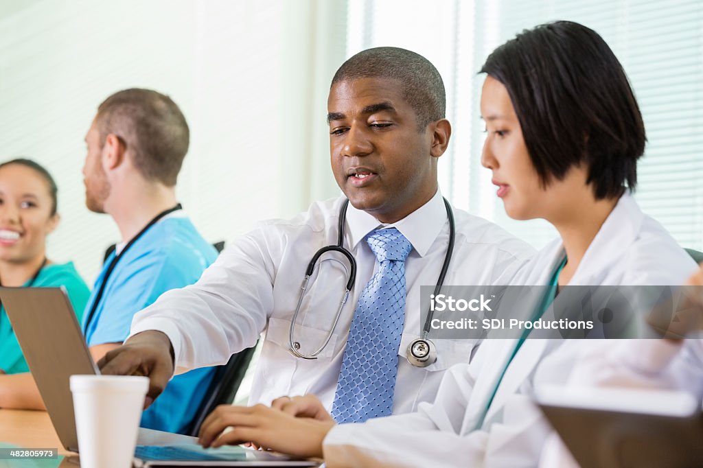 Госпиталь врачей, работающих вместе на ноутбуке во время совещания - Стоковые фото Медбрат роялти-фри