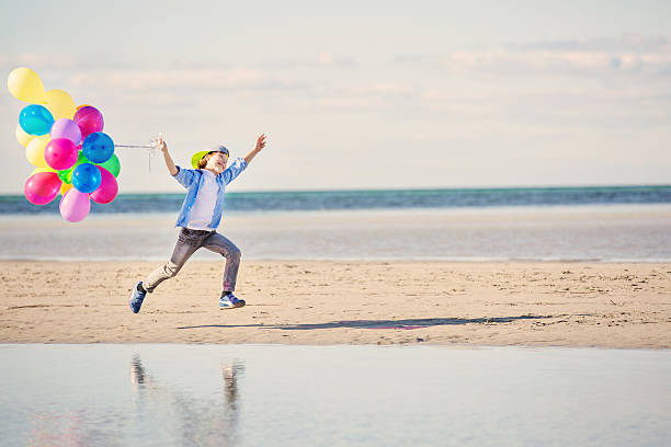 istock Happy boy plays with colored balloons on the beach 482809696