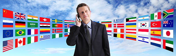 международные бизнесмен, говорящий по телефону, глобальные коммуникации - national flag flag global communications sky стоковые фото и изображения