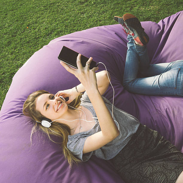 Young Woman At The Park, Listening To Music And Relaxing Young beautiful woman listening to music and relaxing at the park. russian culture audio stock pictures, royalty-free photos & images