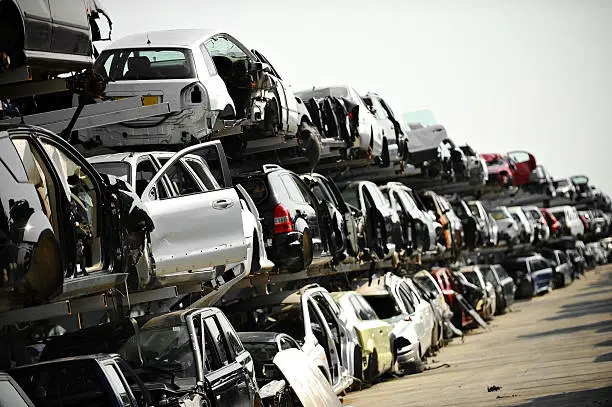 Wrecked vehicles are seen in a car junkyard