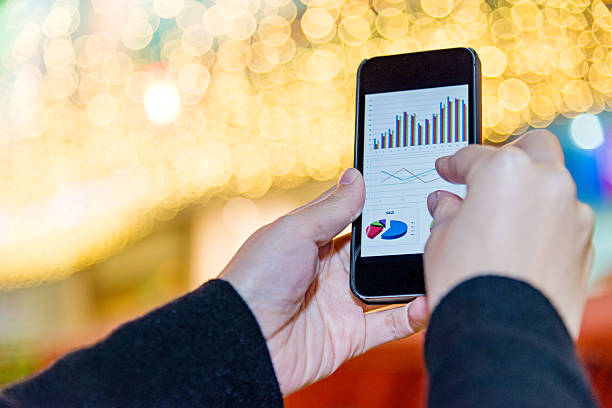 istock holding a smart phone with business chart 482818616