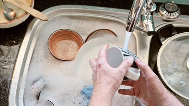istock Male hands doing dishes under running water 482818892