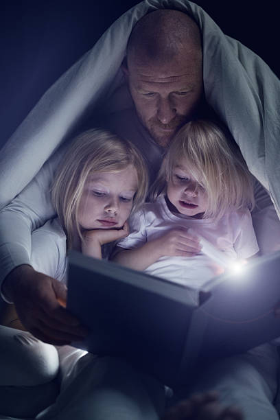istock Father and daughters reading a book at bedtime 482827998