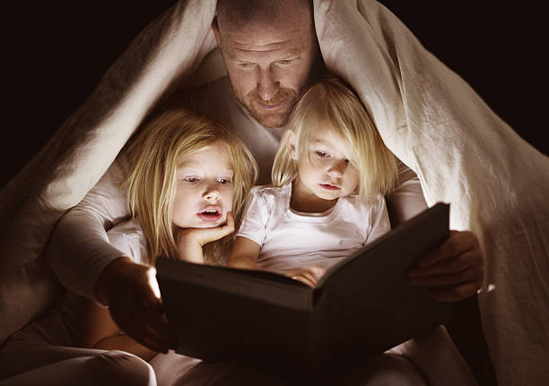 padre e figlie lettura libro all'ora di andare a letto - bedtime stories foto e immagini stock