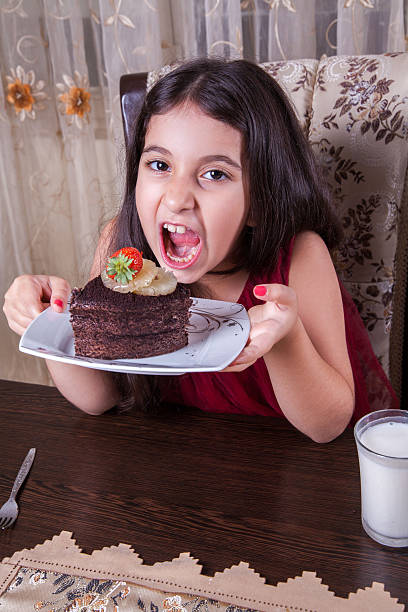 istock smal middle eastern happy girl drinking milk with cake 482829080