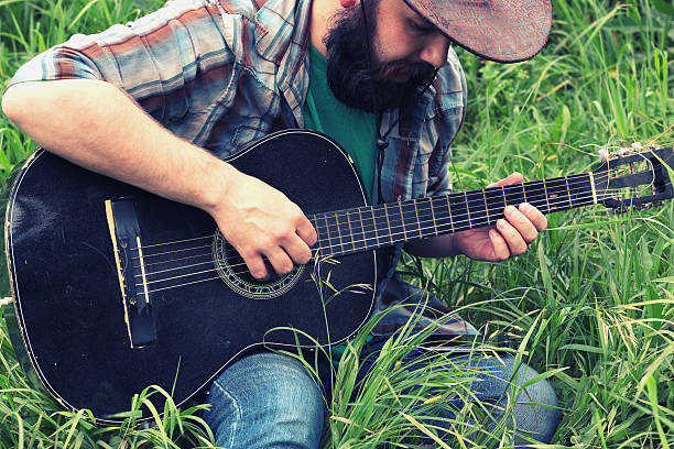 guitarrista en un sombrero de vaquero en la naturaleza - cowboy blue meadow horizontal fotografías e imágenes de stock