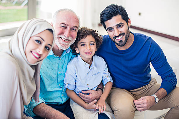 Happy Emirati Family Middle Eastern family portrait, kid, parents and grandfather all looking at the camera. happiness four people cheerful senior adult stock pictures, royalty-free photos & images