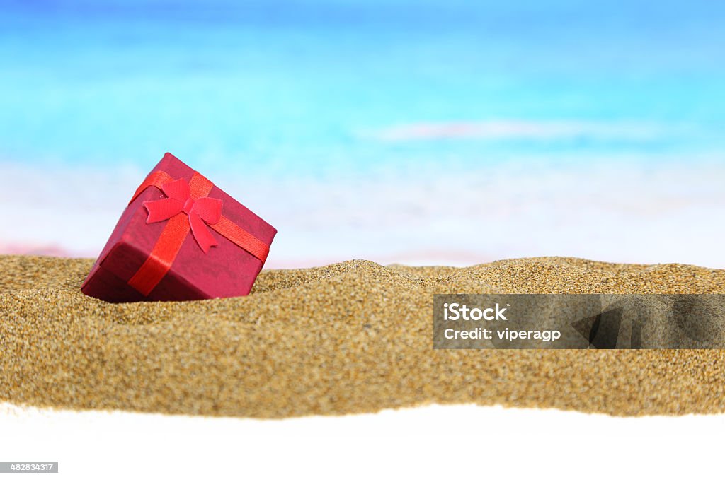 Gift box with ribbon on the sand Christmas Stock Photo