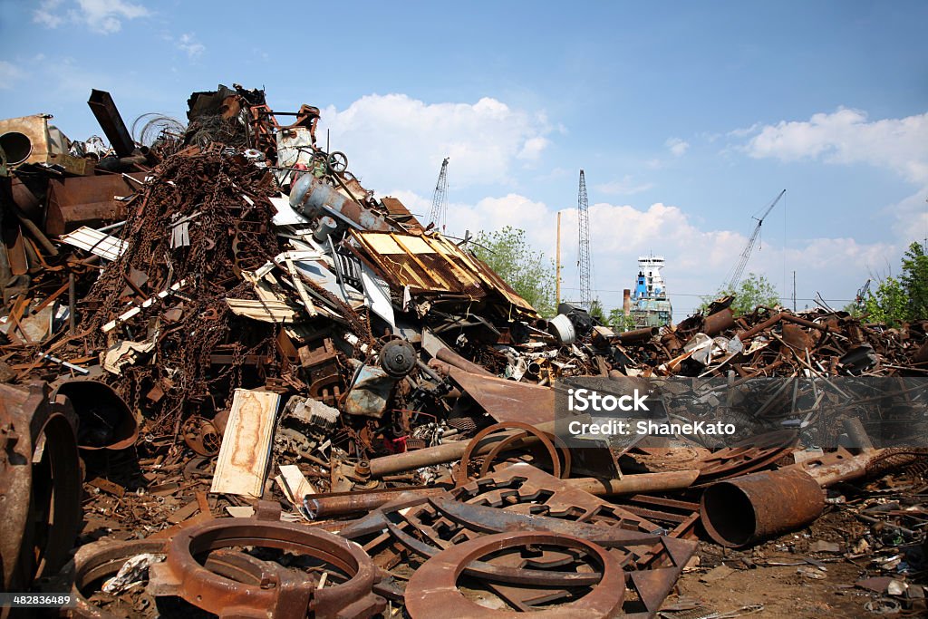 Junkyard Scrap Metal and Shipping Port Large junkyard full of stacks of scrap metal with shipping port in background.  Lots of copy space! Blue Stock Photo