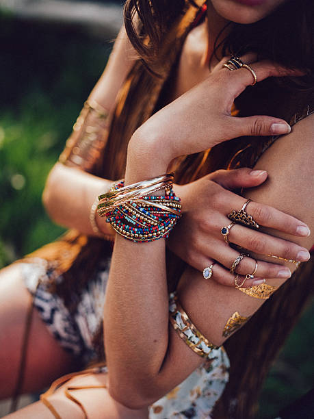 Boho style girl with bangles and rings Cropped shot of a boho style girl sitting outdoors wearing many bangles and rings bohemian fashion stock pictures, royalty-free photos & images
