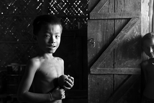 Portrait of a young tribal boy in his home. He is holding a ball in his hands. He is looking directly at the camera. The Boy belongs to the \