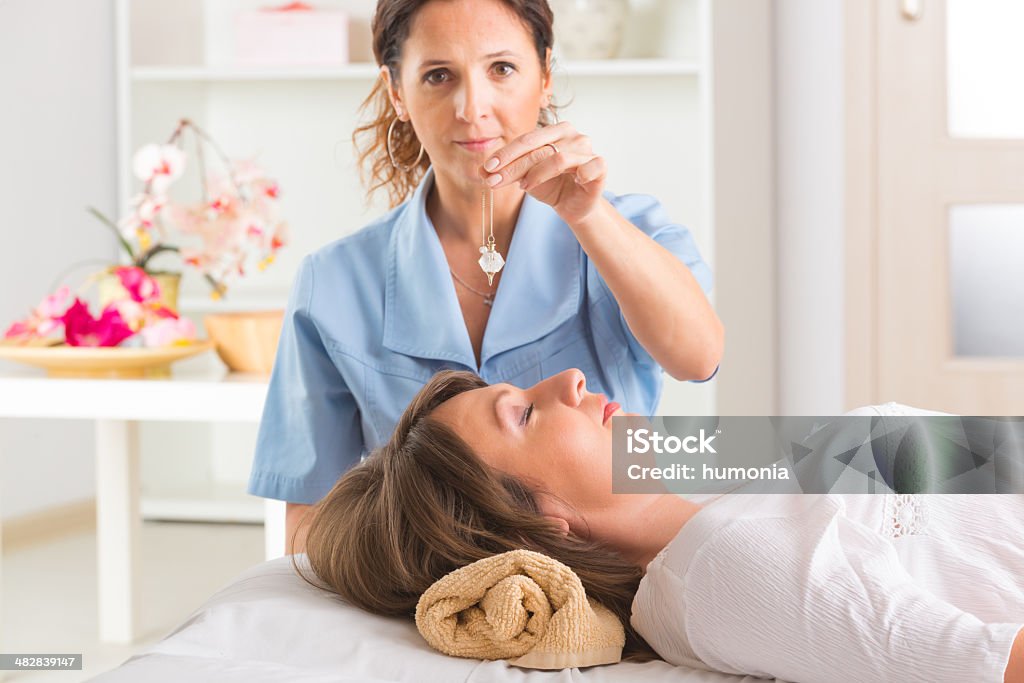 Therapist using pendulum Alternative medicine therapist using pendulum to make a diagnosis Adult Stock Photo