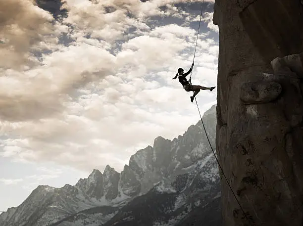 A rock climber rappelling down a cliff in the majestic mountains.   http://blog.michaelsvoboda.com/ConceptBanner.jpg