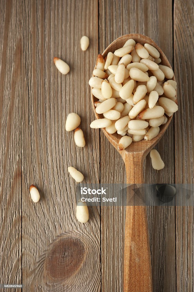 Pine nuts in wooden spoon Peeled pine nuts in wooden spoon on wood background. 2015 Stock Photo