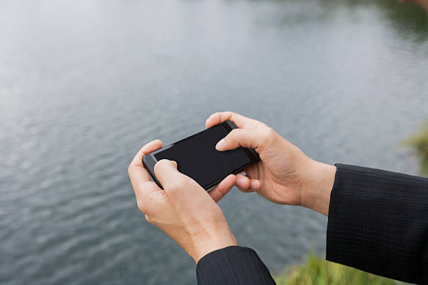 istock Close-up of businessman's hands texting on smart phone along river 482852387