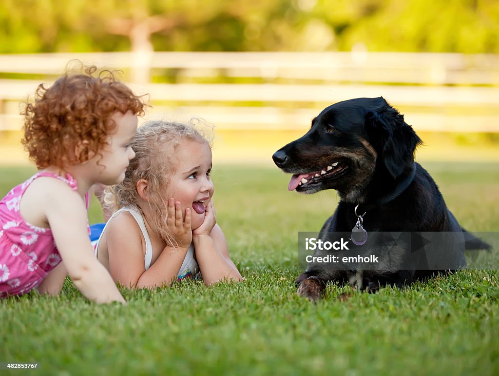 Dwie młode dziewczyny, leżąc w pobliżu czarny rodziny Pies Pet - Zbiór zdjęć royalty-free (Rodzina)