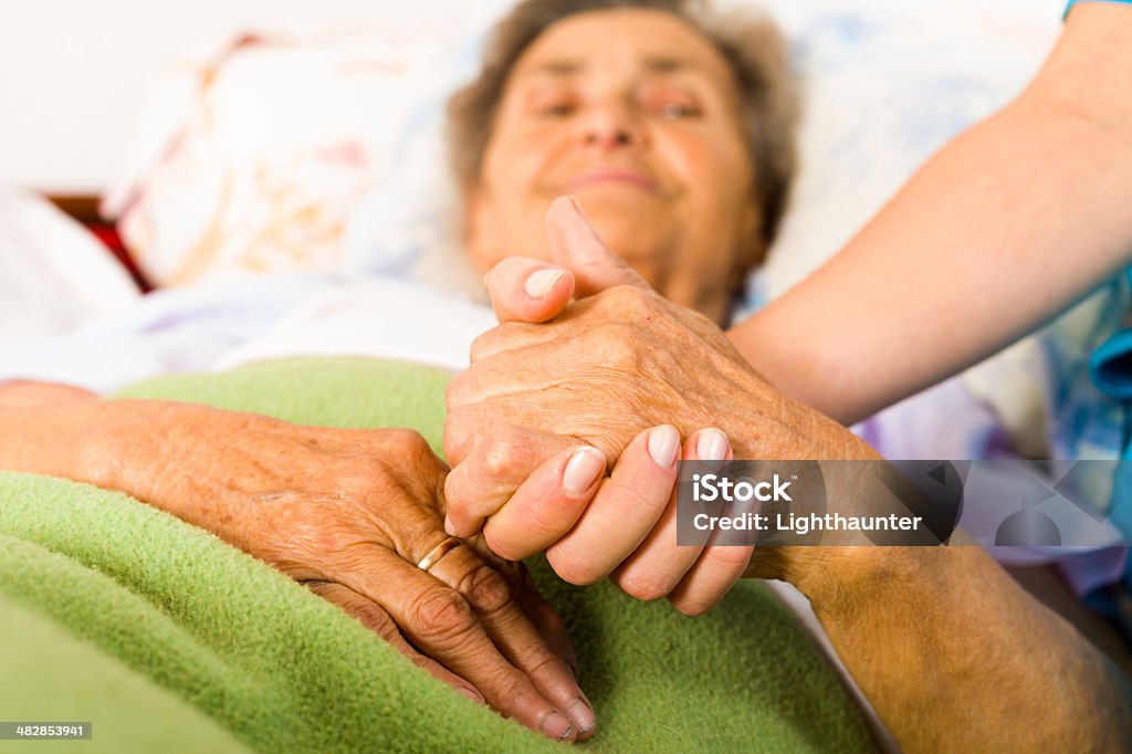 Caring Nurse Holding Hands Health care nurse holding elderly lady's hand with caring attitude. Adult Stock Photo