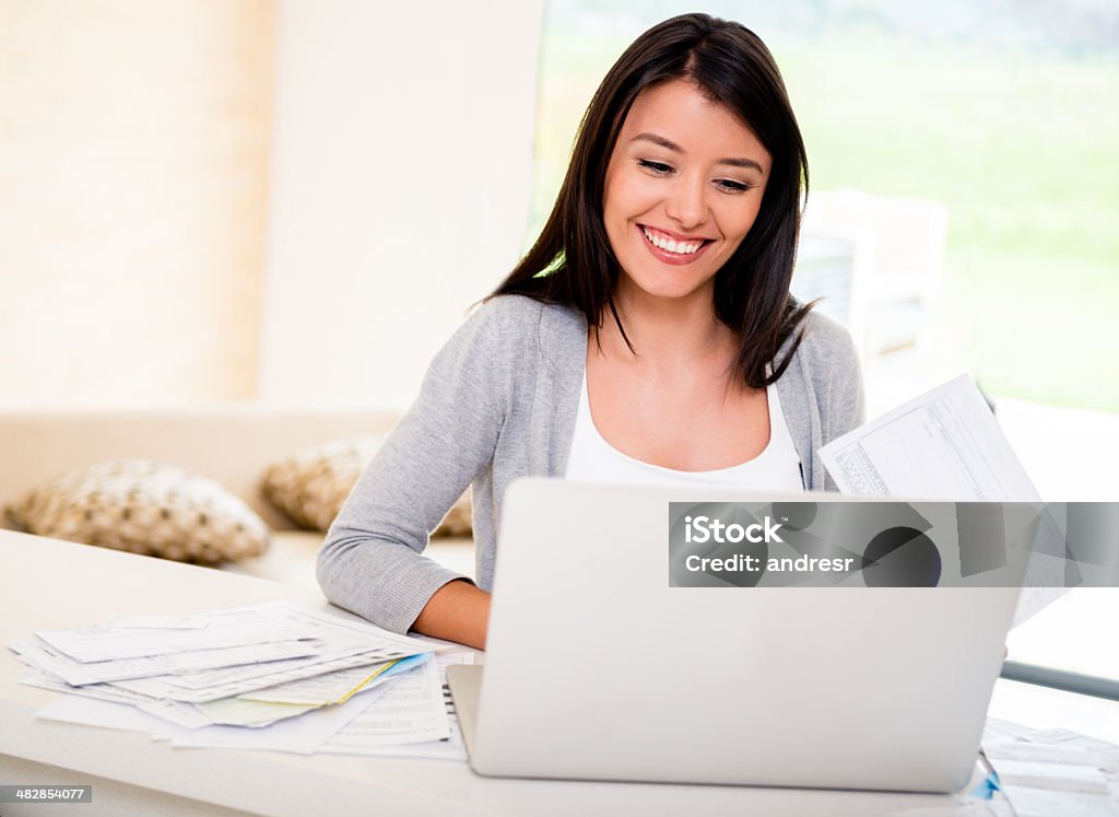 Woman paying bills online Happy woman paying her bills online using the computer Financial Bill Stock Photo