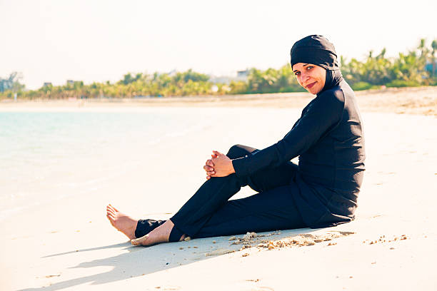young woman wearing burkini sitting by the beach - 回教泳裝 圖片 個照片及圖片檔